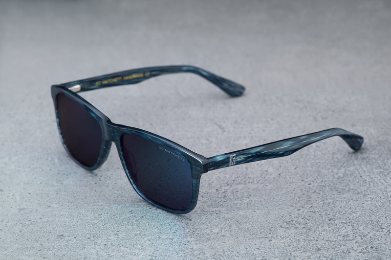 dark blue sunglasses with reflective green lenses, open, facing left showing a quartering view.