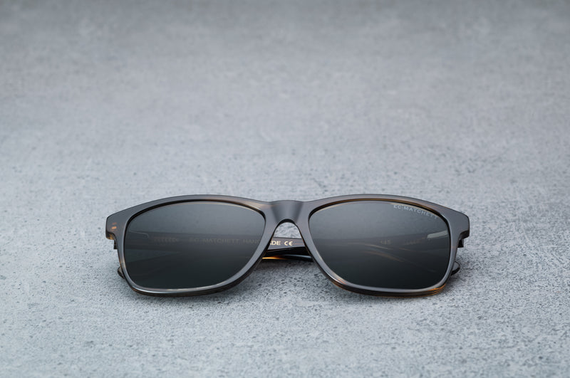 dark brown glasses with dark gray lenses, laying flat, facing forward.