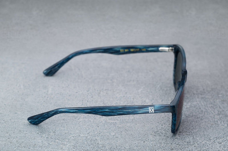 dark blue sunglasses with reflective green lenses, open, facing right showing the frames.